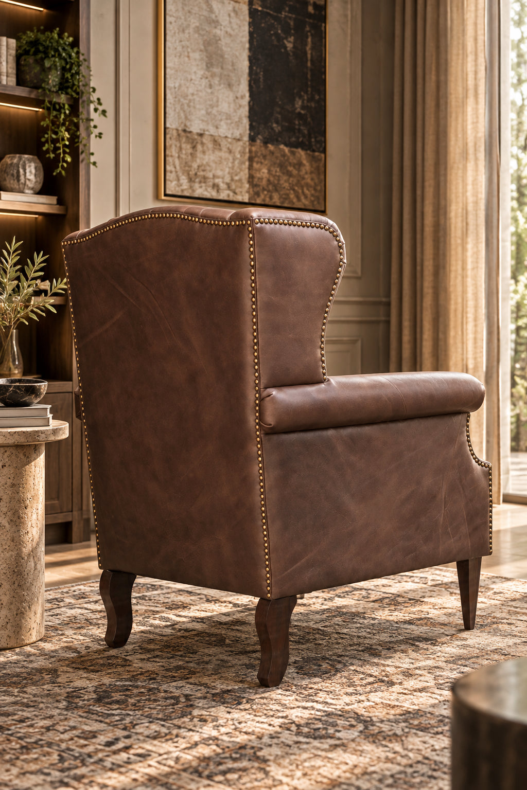 Fully upholstered and studded outside back of the Kasauli leather wing chair with shaped rear legs, Art Avenue made-to-order seating