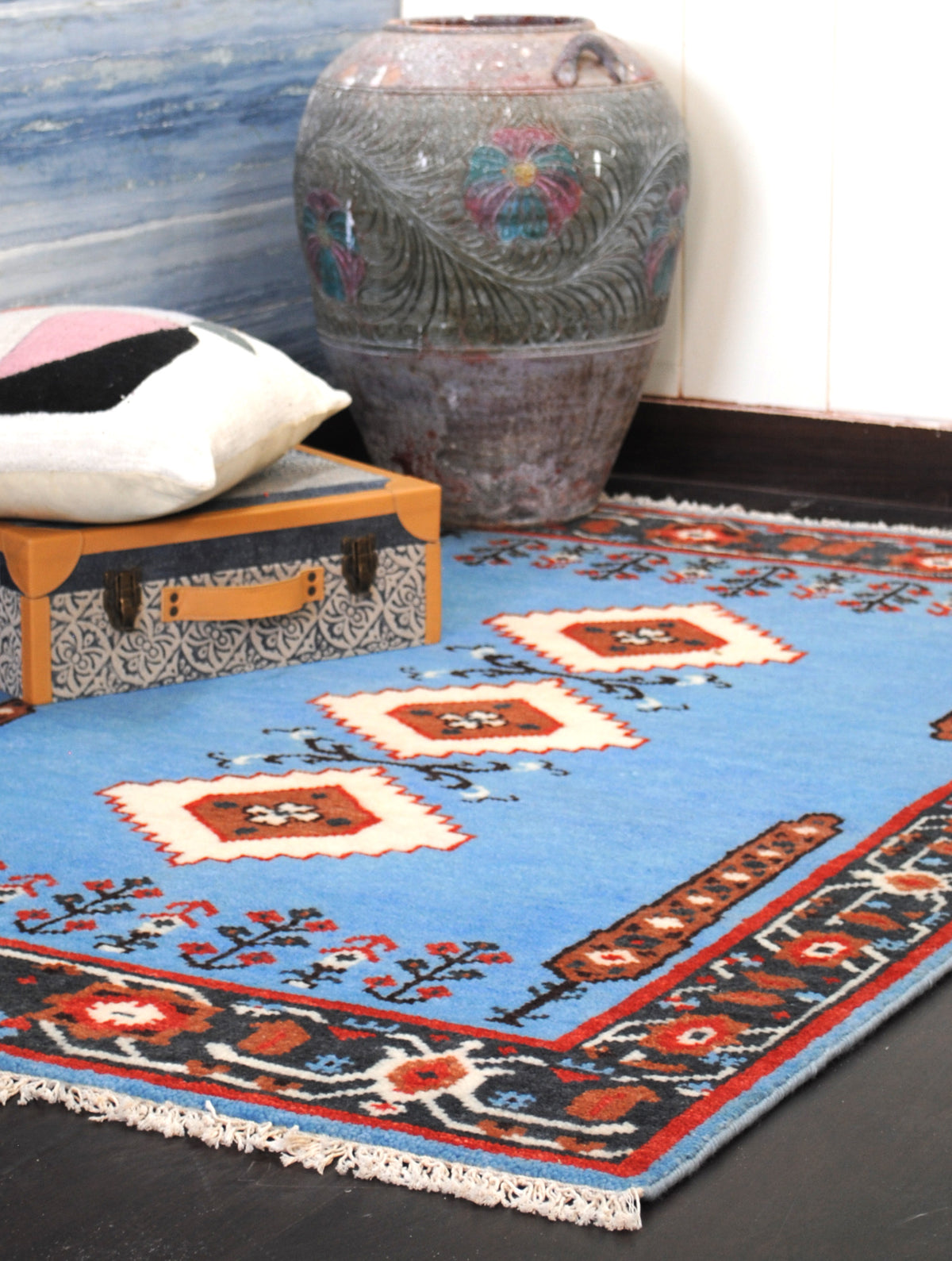 Nilgiri hand-knotted wool rug in a styled corner, close crop of the medallions and border beside a carved urn, Art Avenue