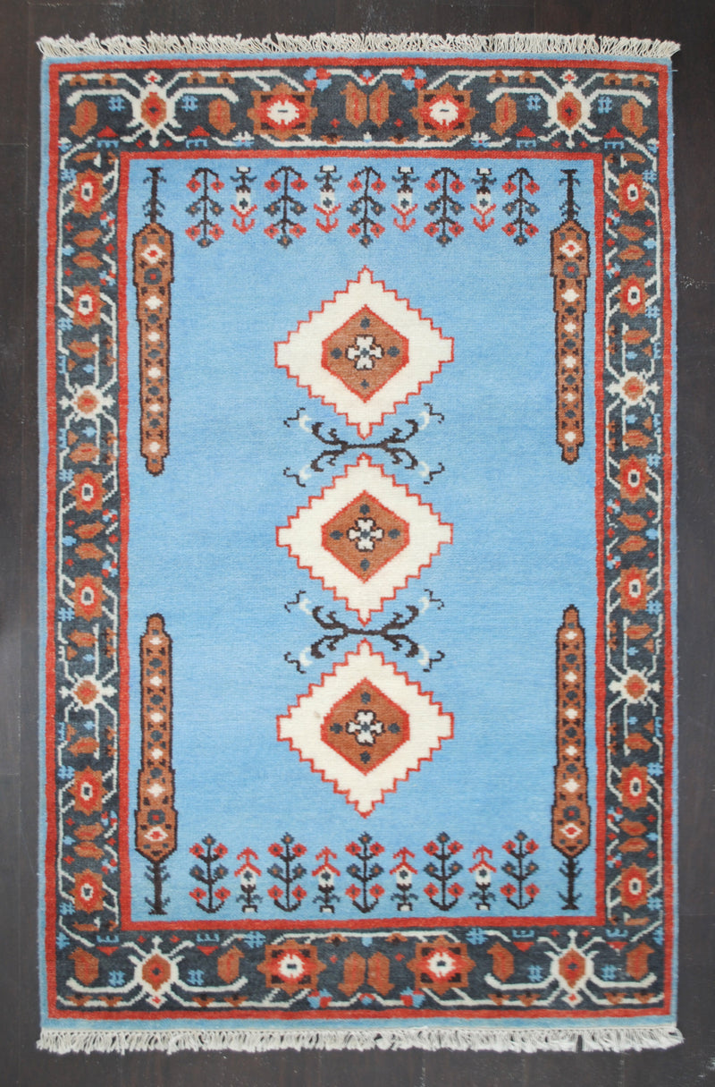 Nilgiri hand-knotted rug in 100% New Zealand wool, full front view: three ivory medallions on a sky-blue field inside a charcoal and brick-red border, Art Avenue, 4×6 ft