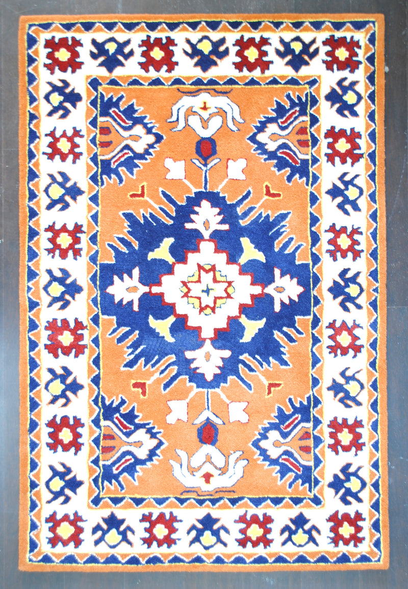 Kutch hand-tufted rug in 100% New Zealand wool, full overhead view: a stepped ivory star in a flaring navy medallion on a saffron field, framed by an ivory border of red and indigo flowers, Art Avenue, 4×6 ft