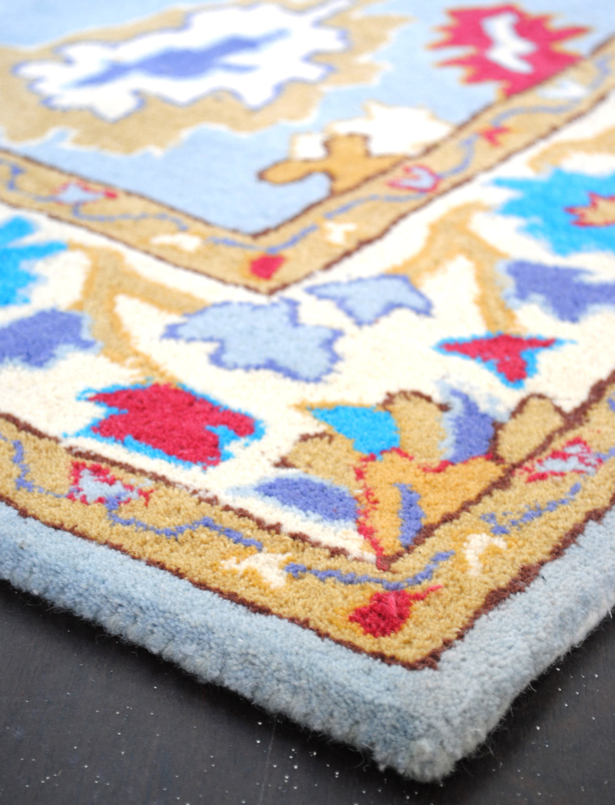 Detail of the Agra rug's dense New Zealand wool pile and hand-bound pale blue edge
