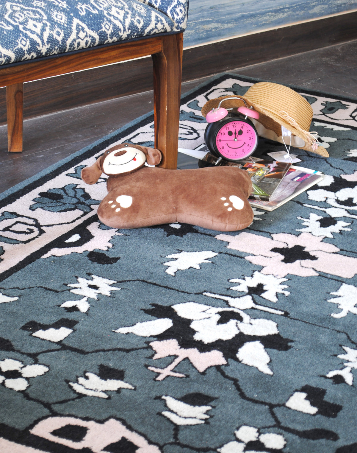 Ivory and blush blossoms on black stems across the slate grey field of the Shimla rug
