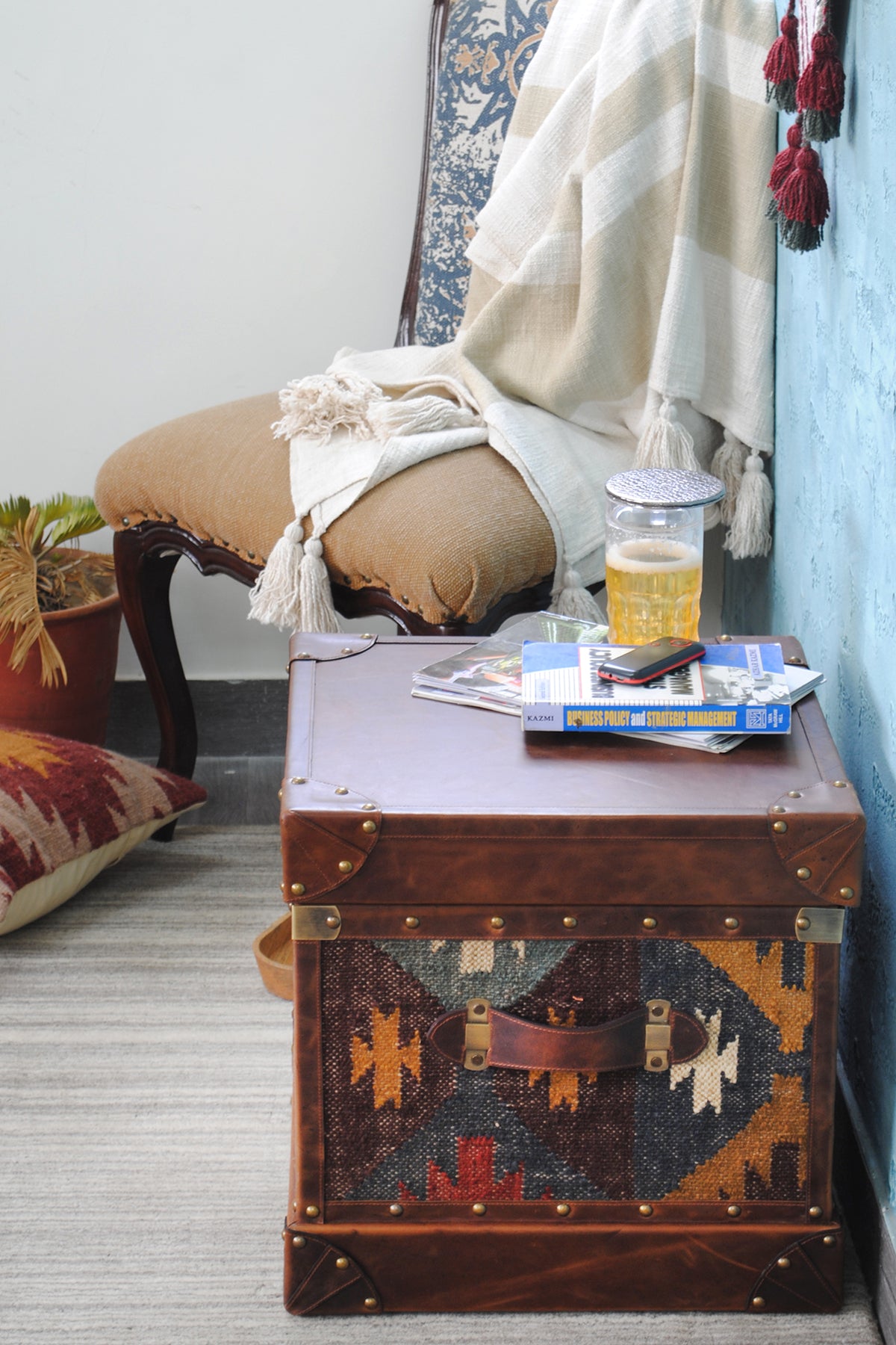 Madras kilim trunk beside an upholstered chair, showing side-table height in a living room