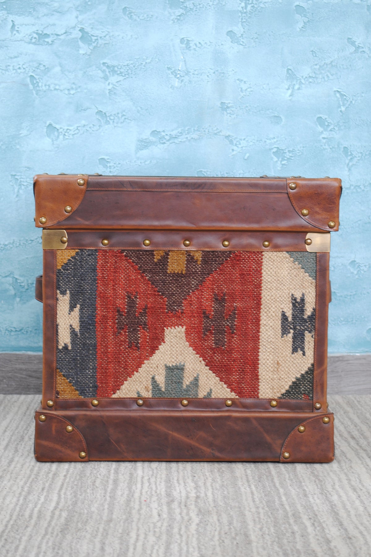 Side elevation of the Madras kilim trunk showing brass corner brackets at the lid line