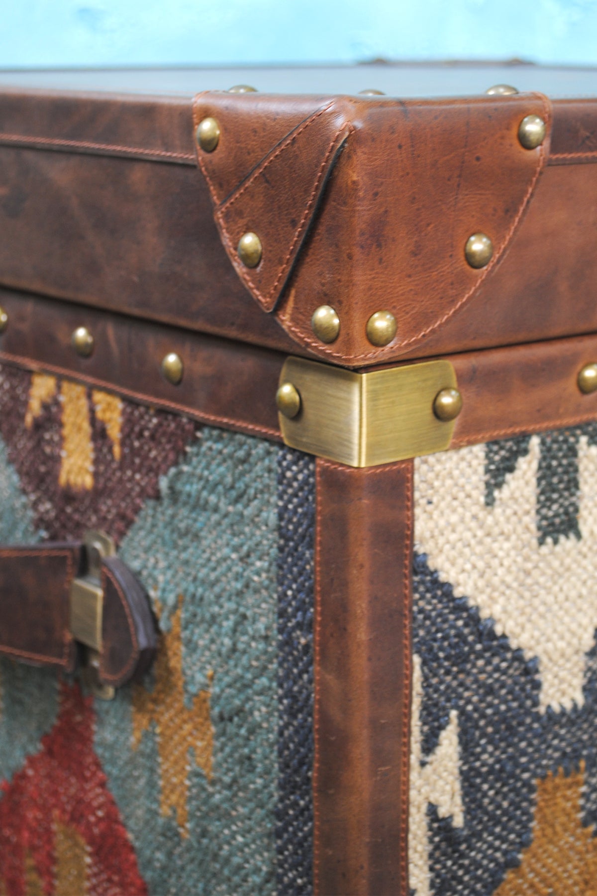 Corner detail of the Madras trunk: brass corner bracket, domed studs and shaped leather corner cap
