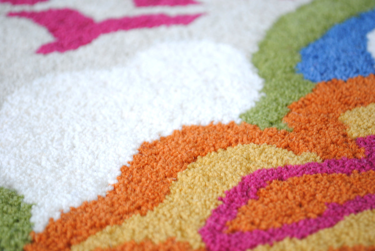 Close-up of the Ooty rug's New Zealand wool pile, with ivory, orange, marigold, fuchsia, olive and cornflower blue laid in flat blocks