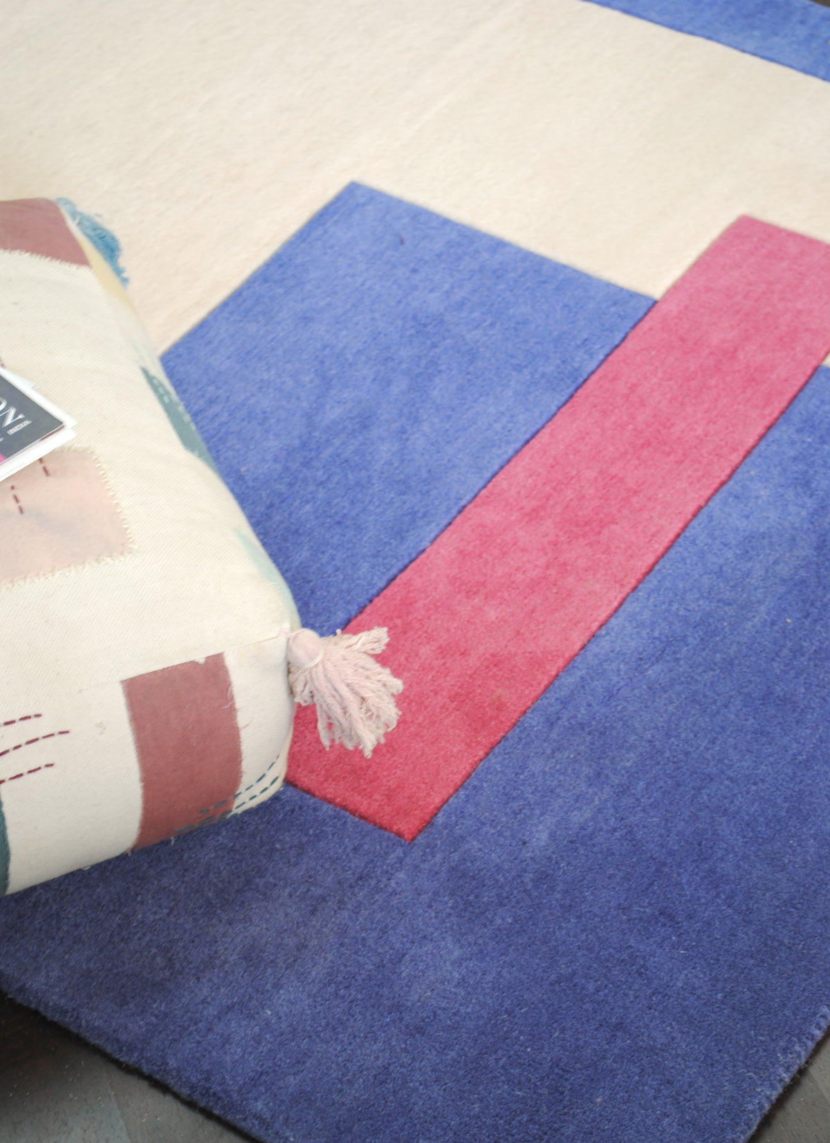 Close view of the raspberry bar crossing the cobalt field of the Mahe rug