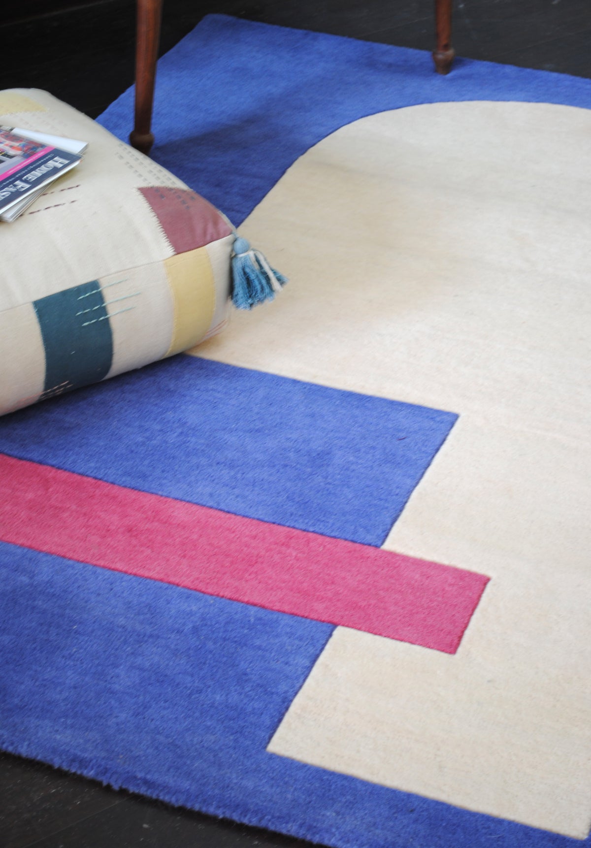 Angled view of the Mahe rug's ivory arch and raspberry bar on cobalt blue