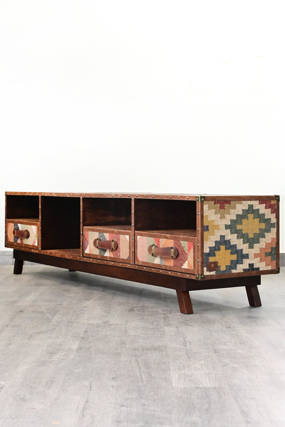 Ranakpur TV unit in the studio at a three-quarter angle, full-height vintage kilim flank and brass corner caps