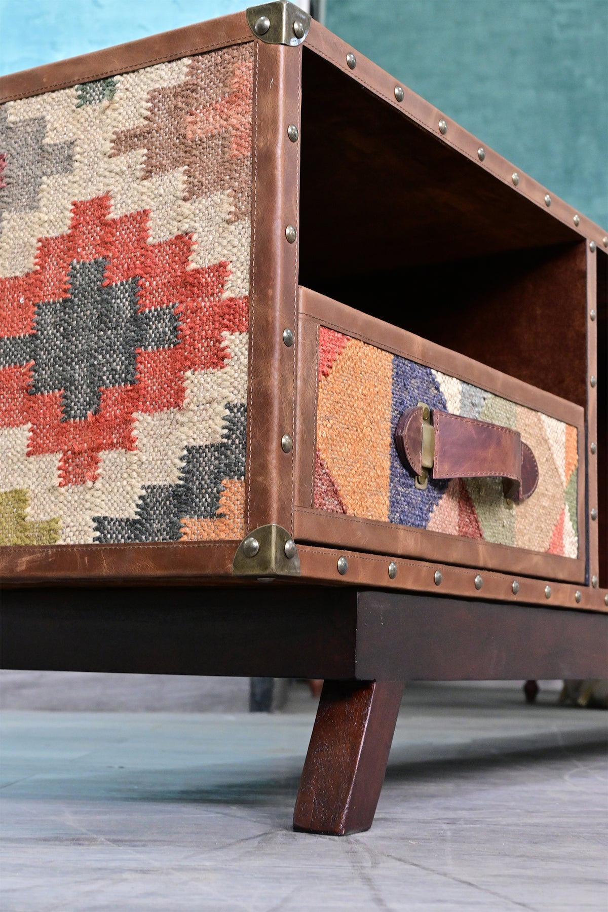 Low angle of the Ranakpur TV unit's kilim flank, brass corner caps, kilim drawer front and tapered solid wood leg