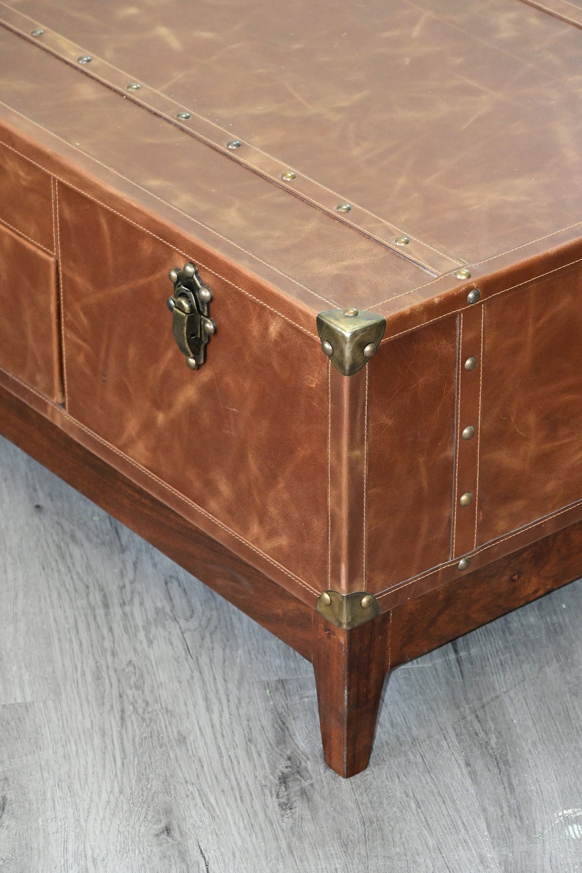 Kuchaman leather trunk coffee table corner detail: metal corner caps, saddle stitching and tapered solid wood leg