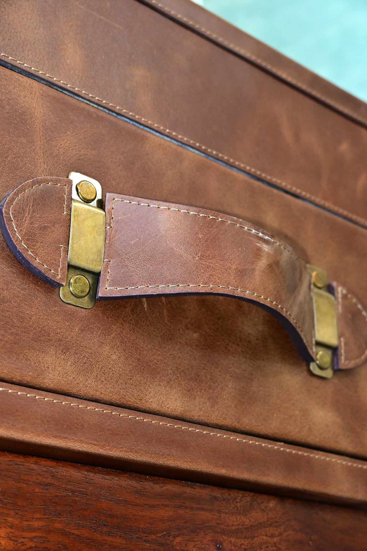 Kuchaman leather trunk coffee table, close-up of the stitched leather strap handle on metal mounts