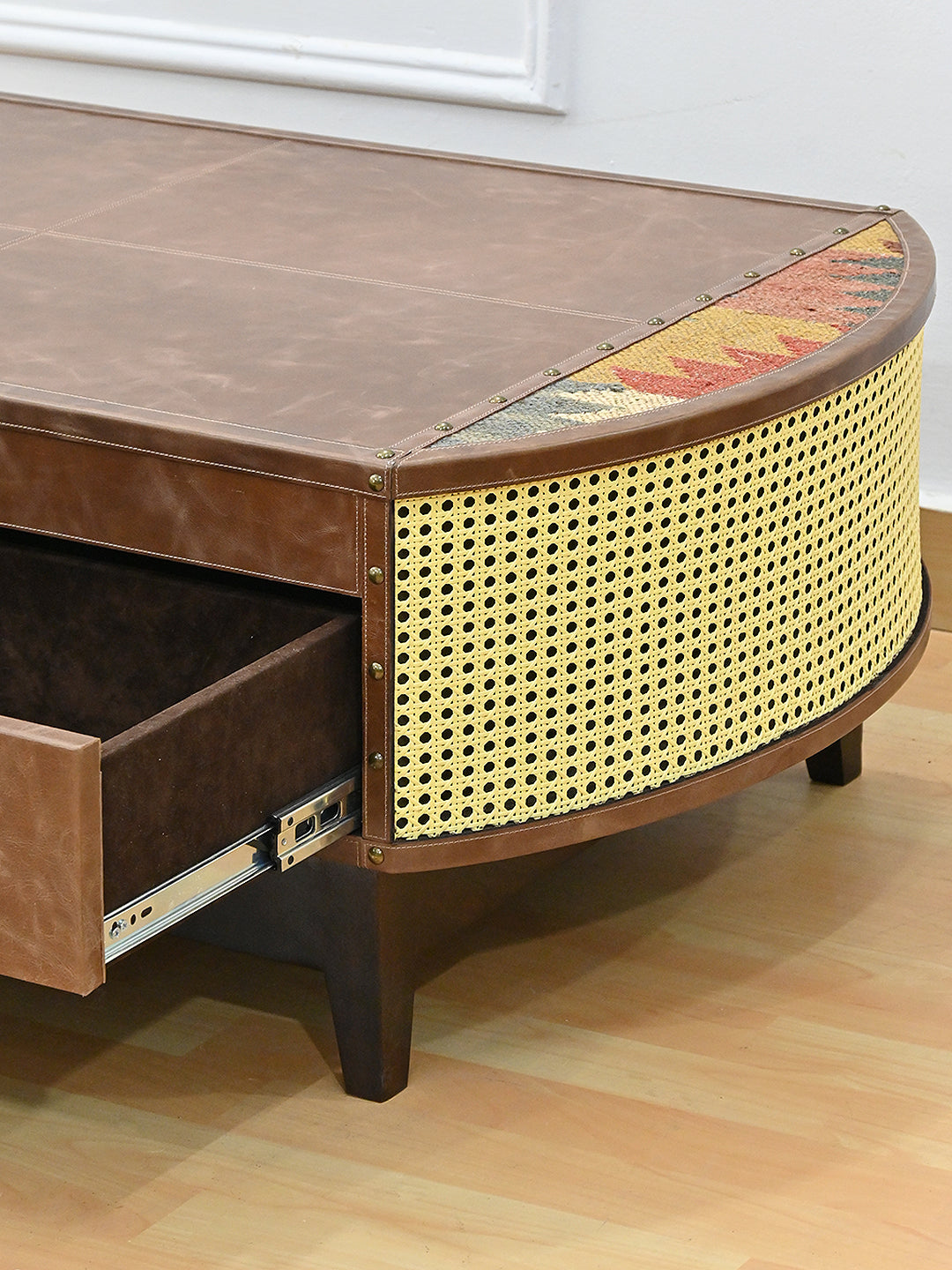 Detail of the Bisalpur coffee table: curved cane end, open drawer and tapered solid wood leg