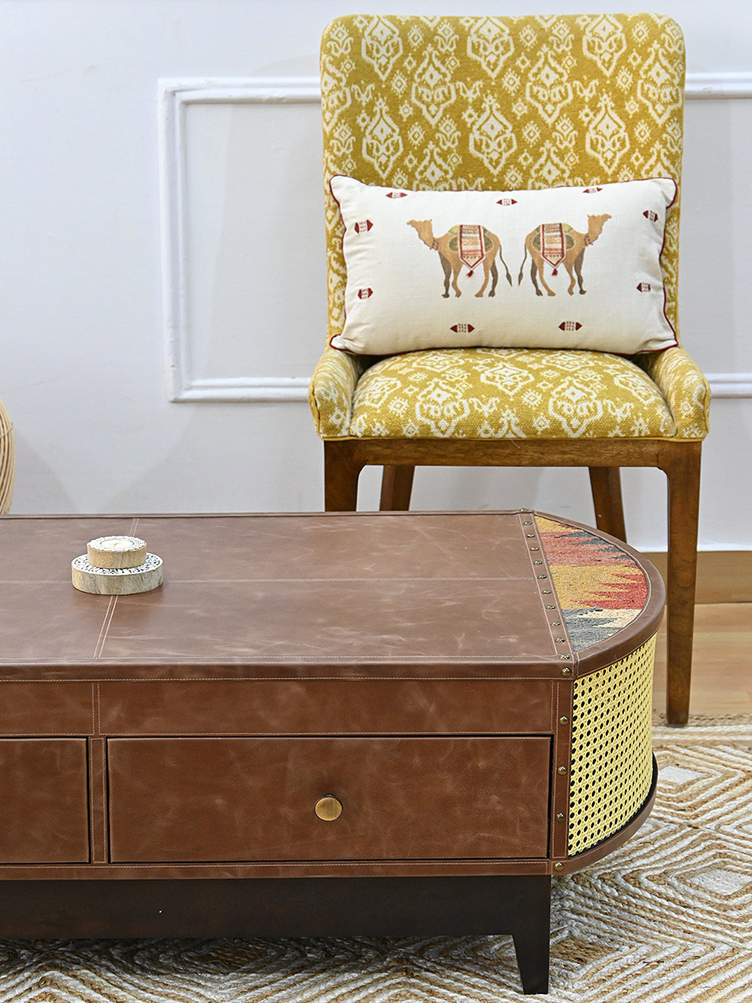 Bisalpur coffee table corner with a yellow ikat chair and camel-motif cushion behind