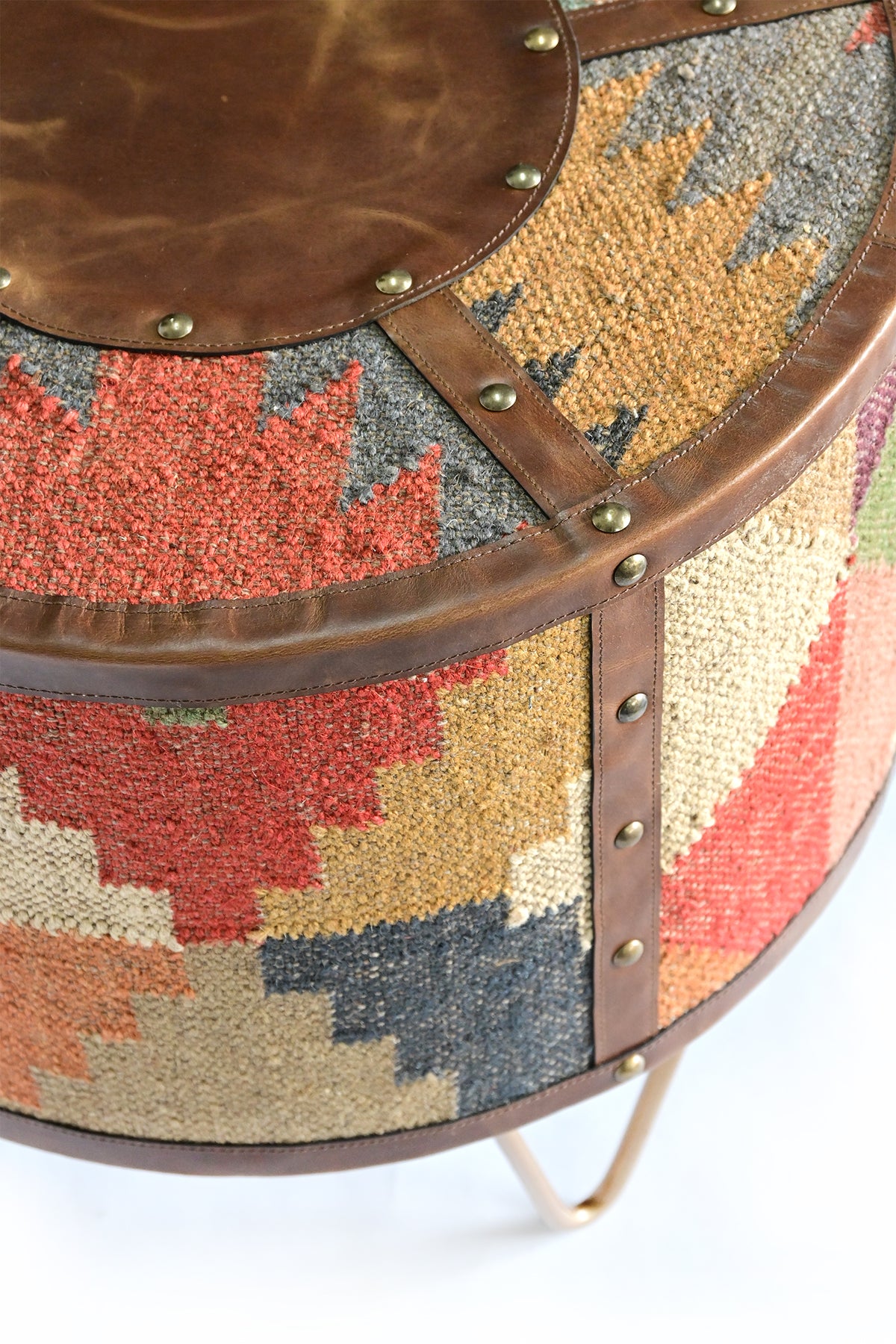 Close-up of the Alwar side table's stitched leather rim, brass studs and handwoven kilim