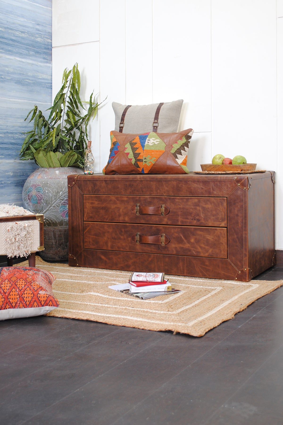 Deogarh leather drawer trunk styled in a living room with kilim cushions, a jute rug and a potted plant