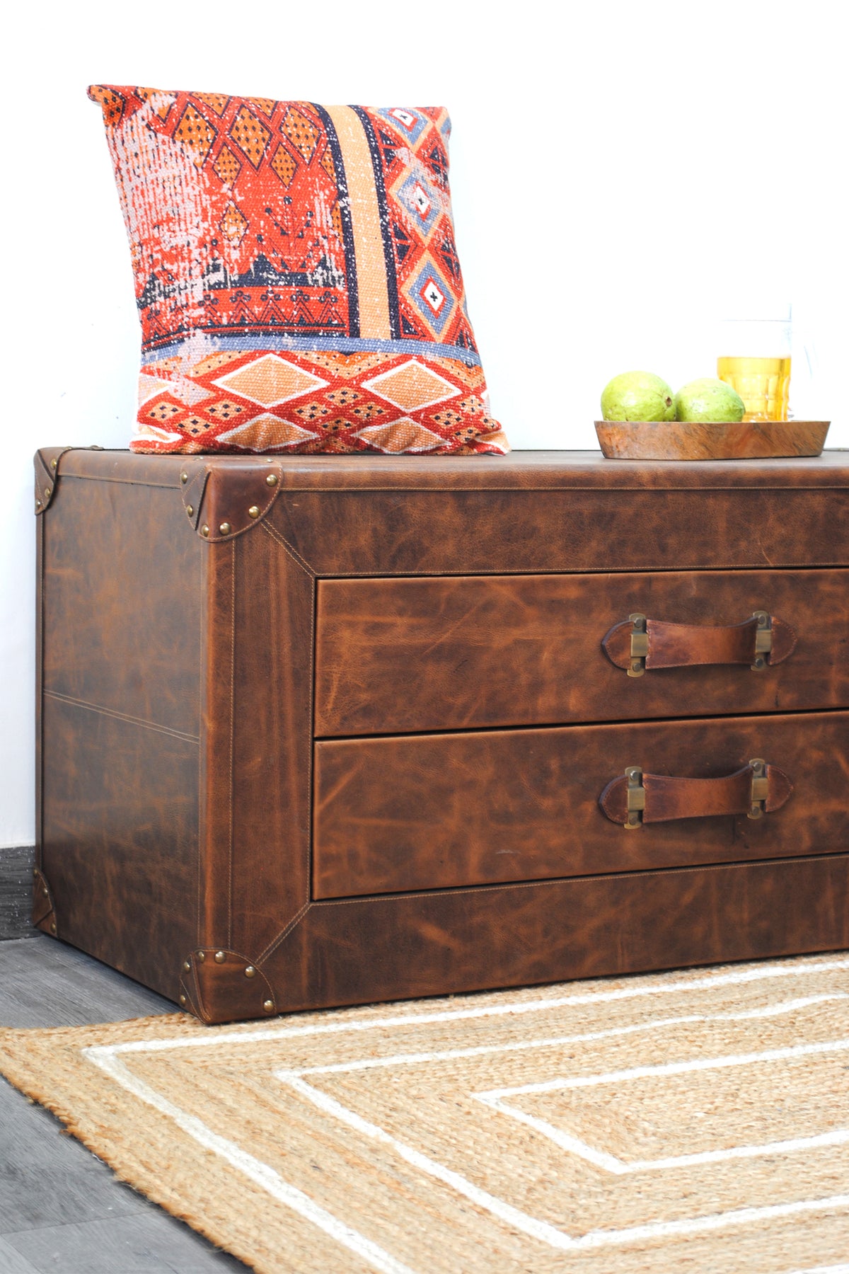 Close view of the Deogarh trunk corner showing riveted brass caps and twin-needle stitched leather seams
