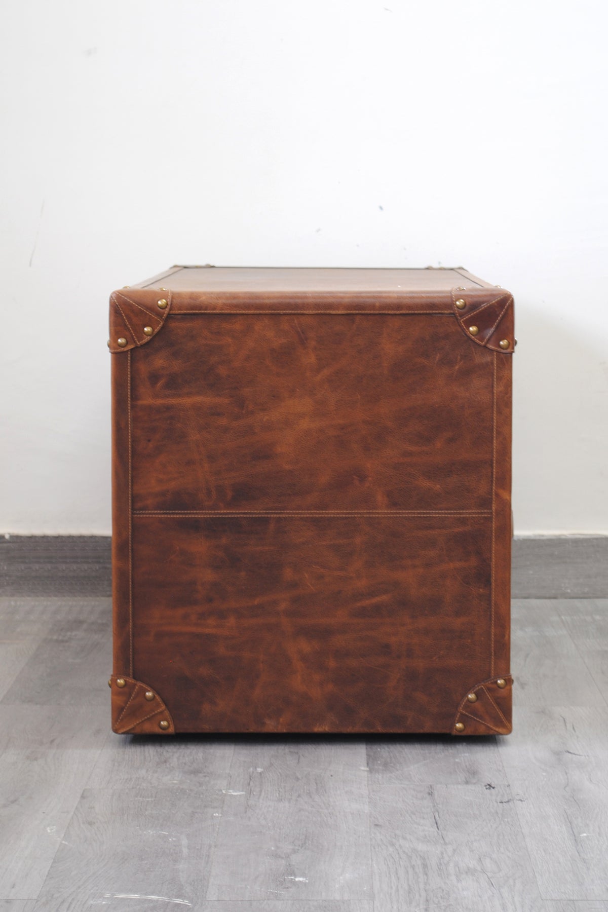 End elevation of the Deogarh leather drawer trunk showing full leather cladding and riveted brass corners