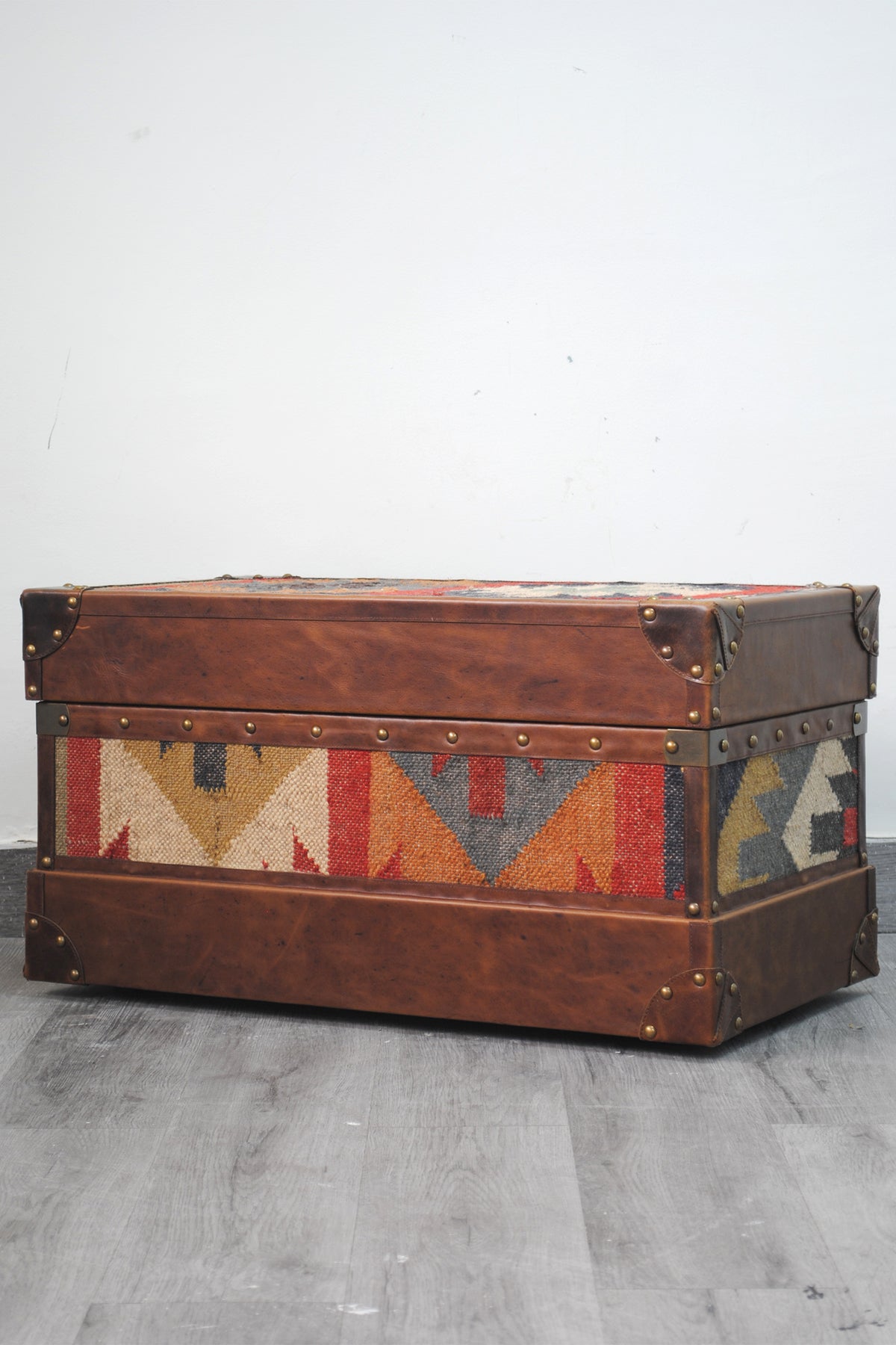 Three-quarter view of the Bundi kilim steamer trunk showing the front and side kilim panels