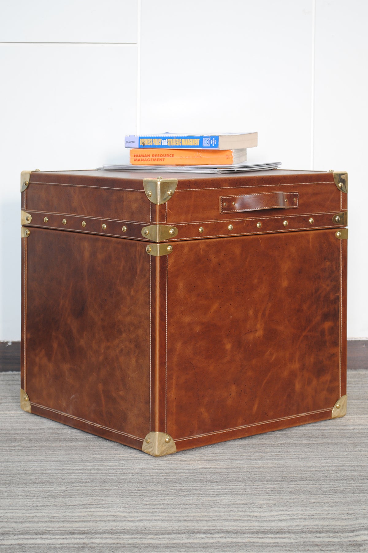 Cordoba Leather Cube Trunk, three-quarter view showing cognac leather, studded lid band and brass corners