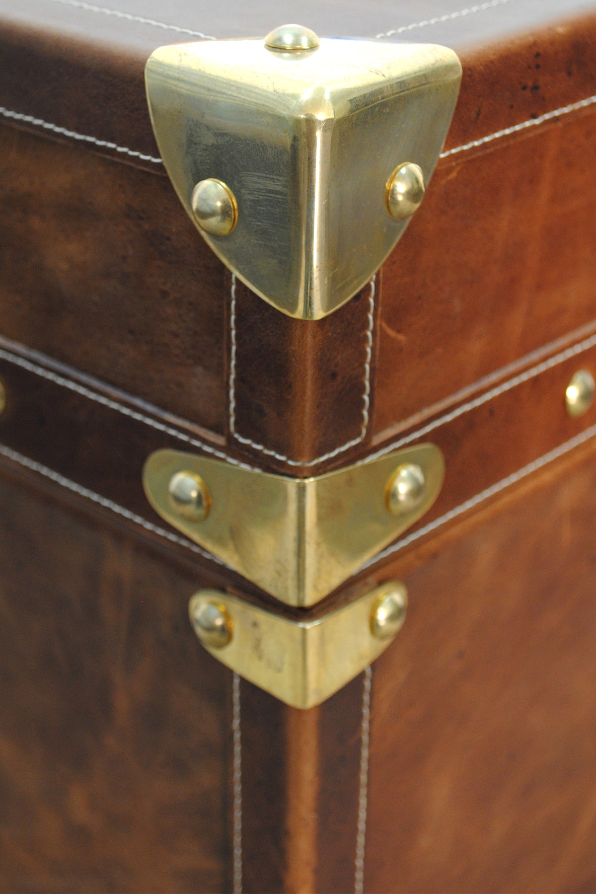 Brass corner cap and lid-seam brackets with contrast topstitching on the Cordoba trunk