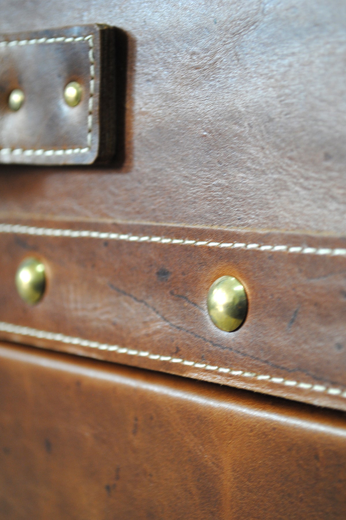 Dome-head brass studs on the leather lid band of the Cordoba trunk