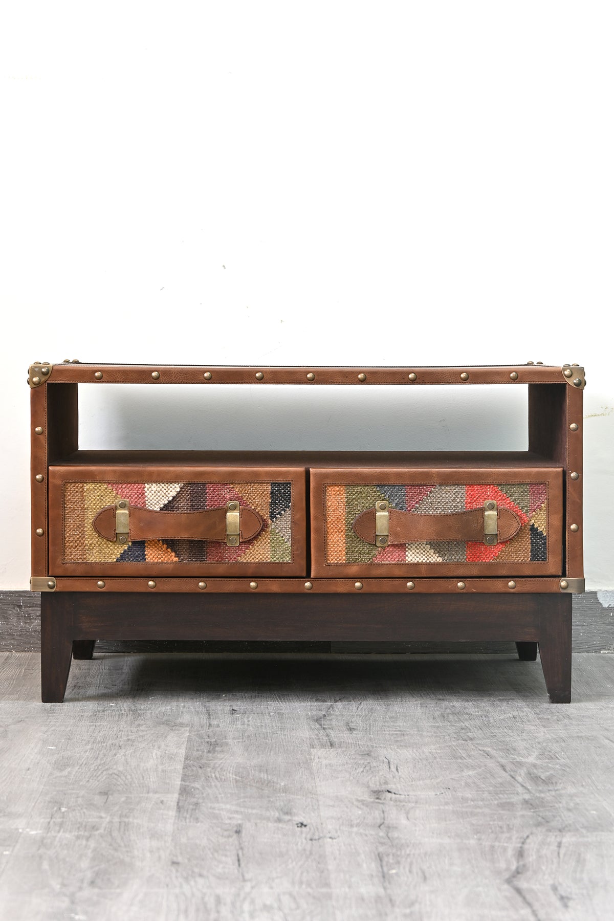 Barmer kilim and leather TV unit seen from the front, open bay above two kilim-panelled drawers on a dark wood base
