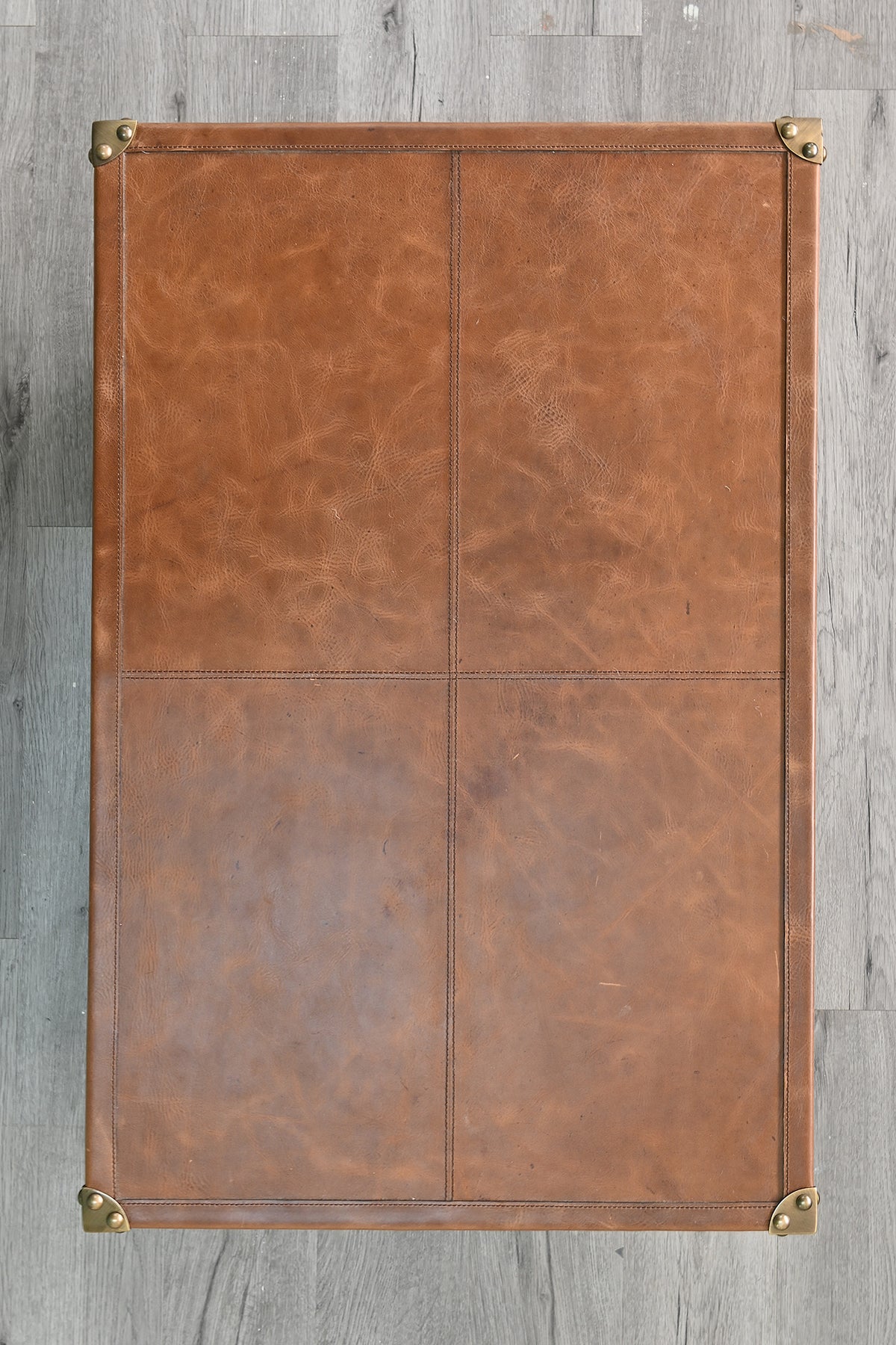 Overhead view of the Barmer TV unit's leather top, showing stitched seams and brass corner caps