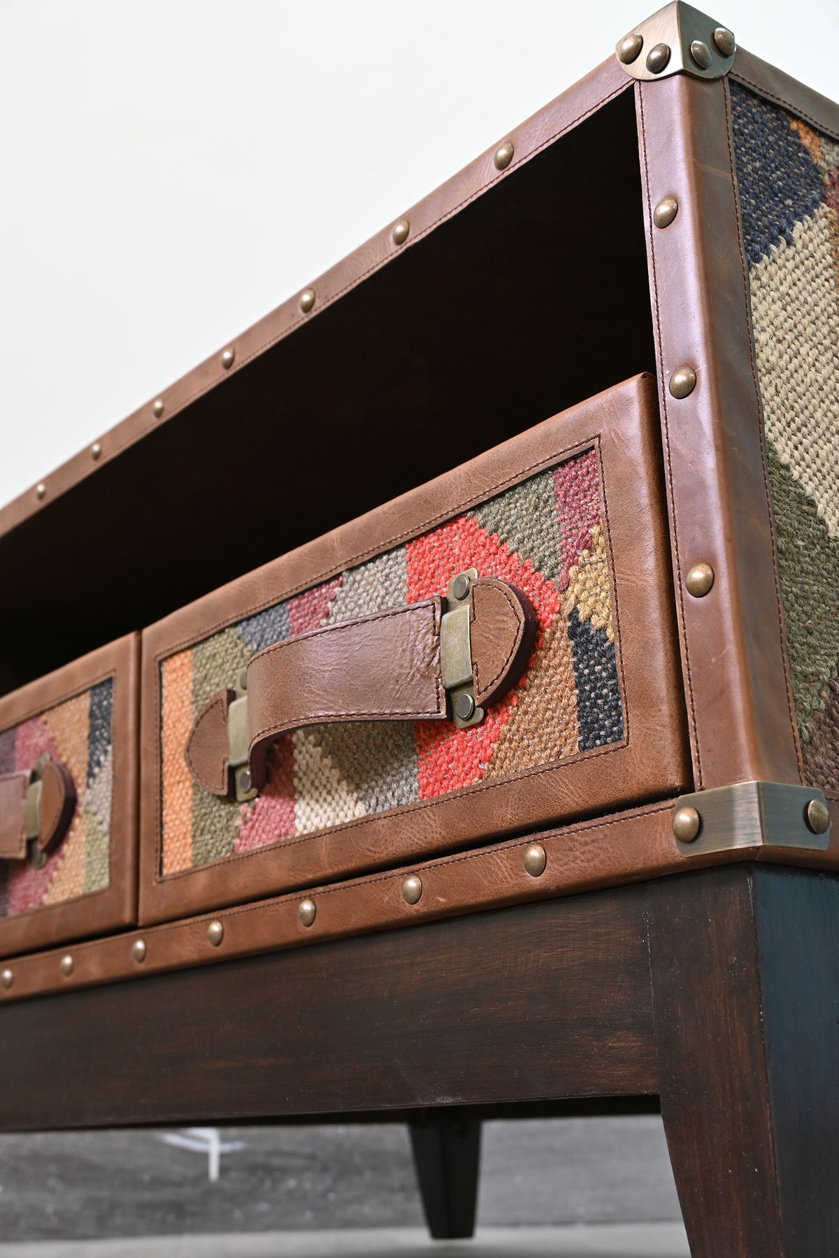 Close detail of the Barmer TV unit's leather-clad corner, domed studs and brass corner cap