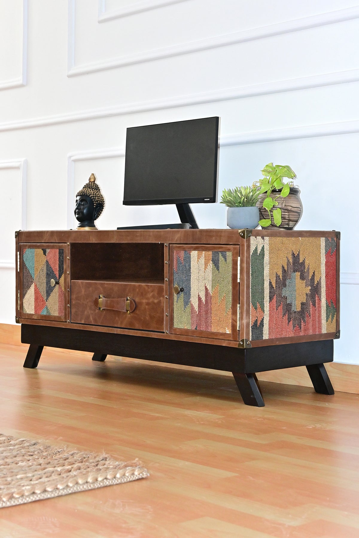 Low angle of the Karauli TV unit showing the kilim flank and splayed wood legs