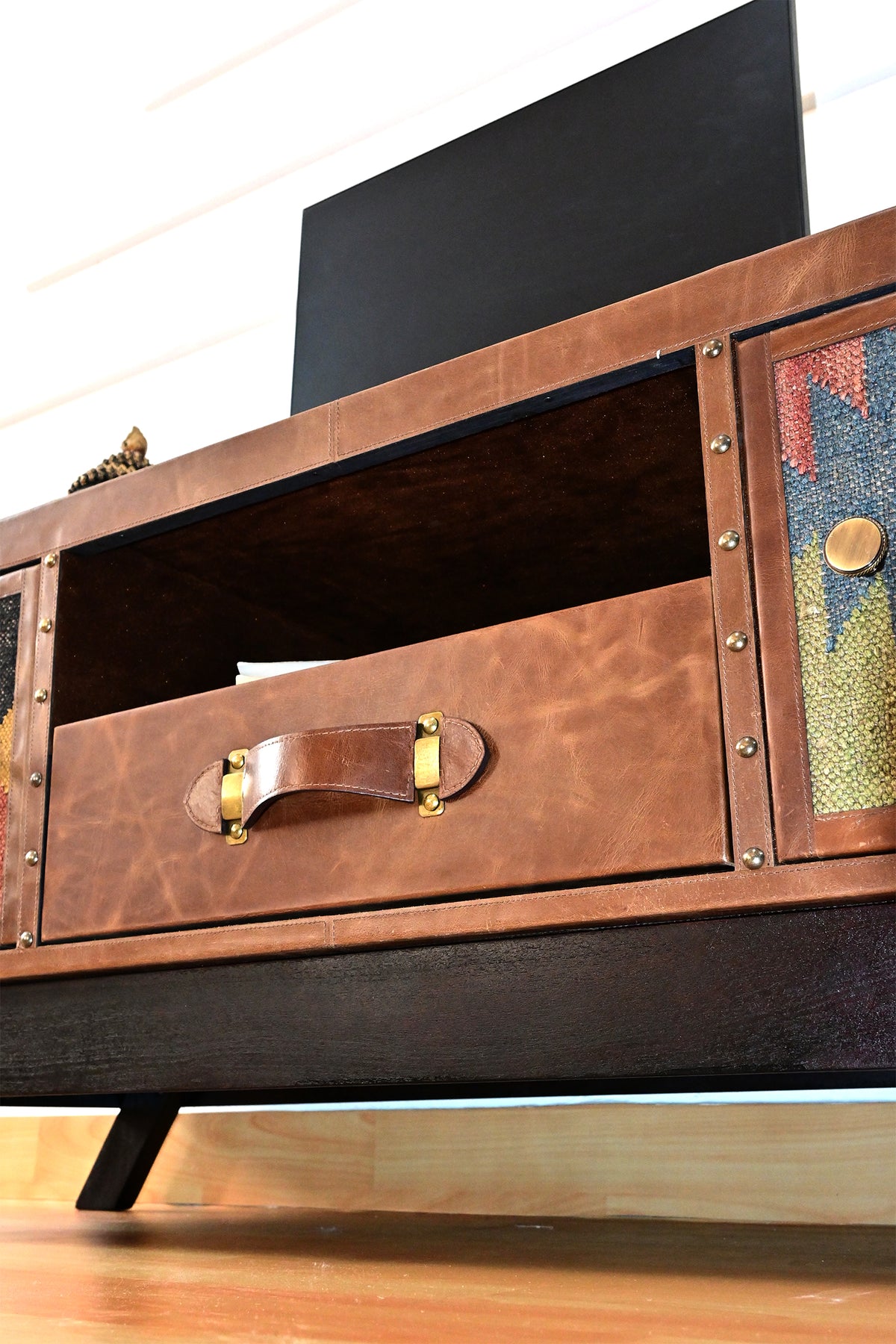 Leather-faced drawer with strap handle below the open shelf, edged with brass studs