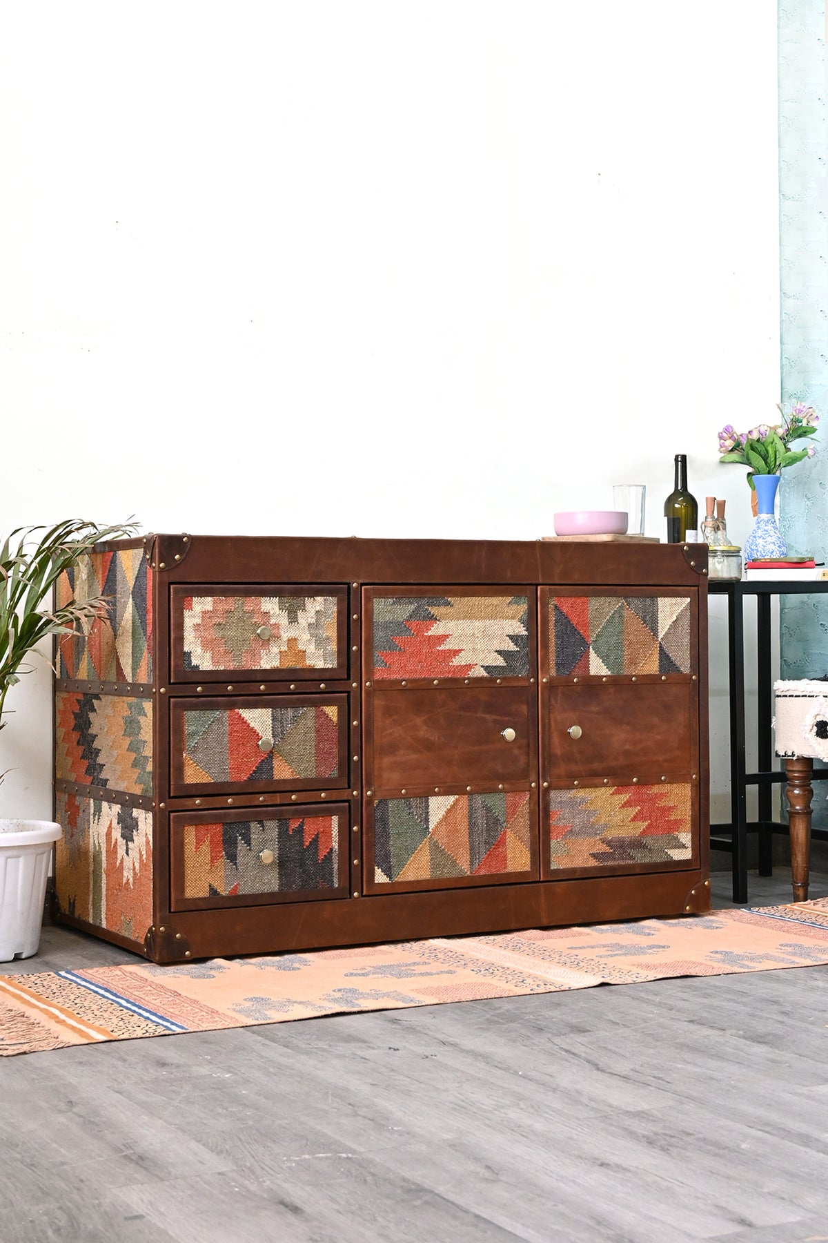 Nimaj Kilim & Leather Sideboard styled at an angle beside a plant, kilim-clad side and leather-bound front — Art Avenue, made to order