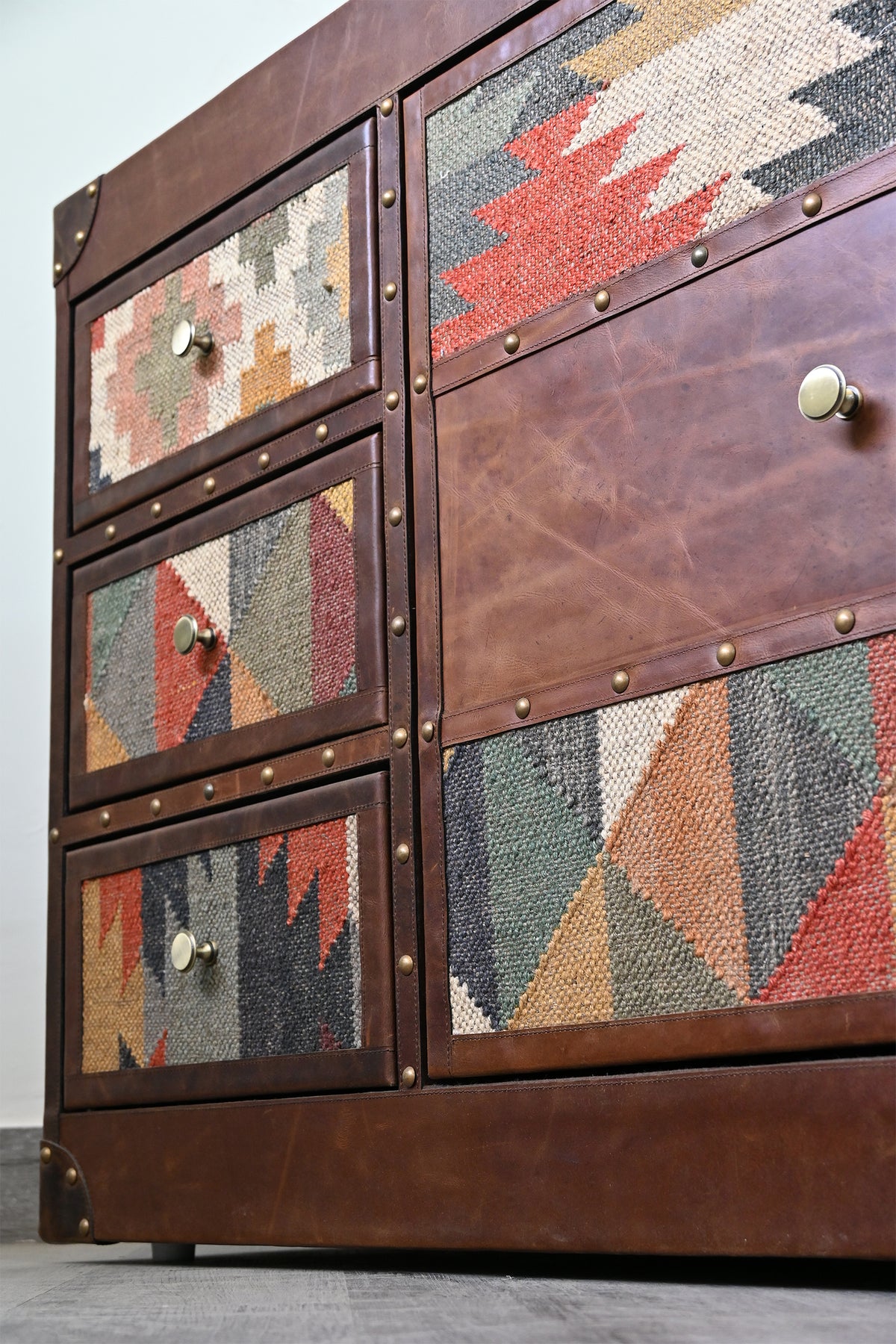 Close-up of the Nimaj sideboard's kilim drawer fronts, tiered kilim-and-leather door and brass-studded leather bands — Art Avenue