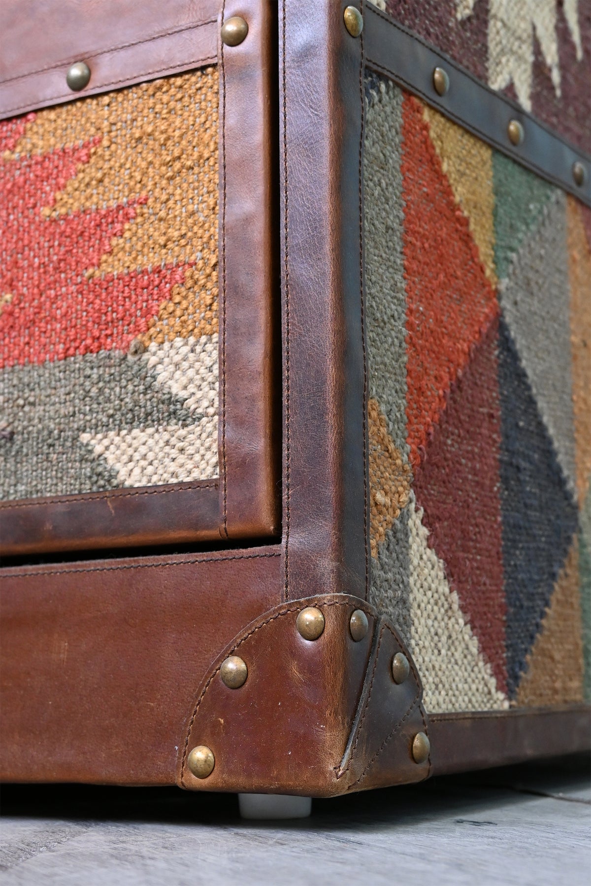 Leather-bound base corner of the Nimaj sideboard with brass studs beside a vintage kilim side panel — Art Avenue