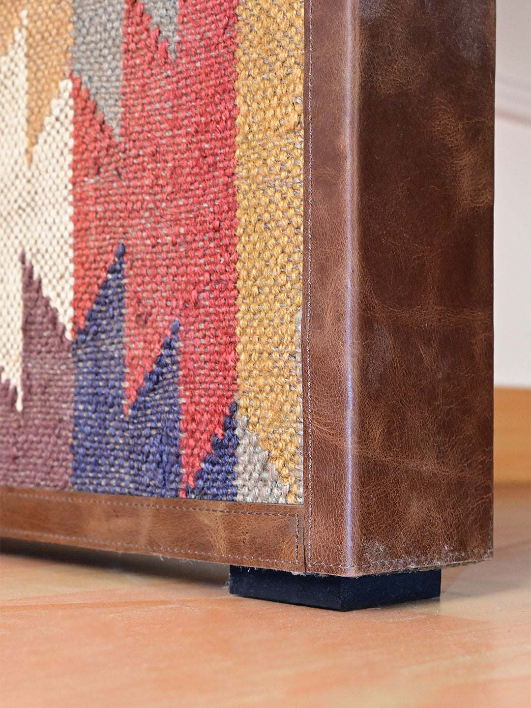Detail of the leather-bound kilim leg and low black foot