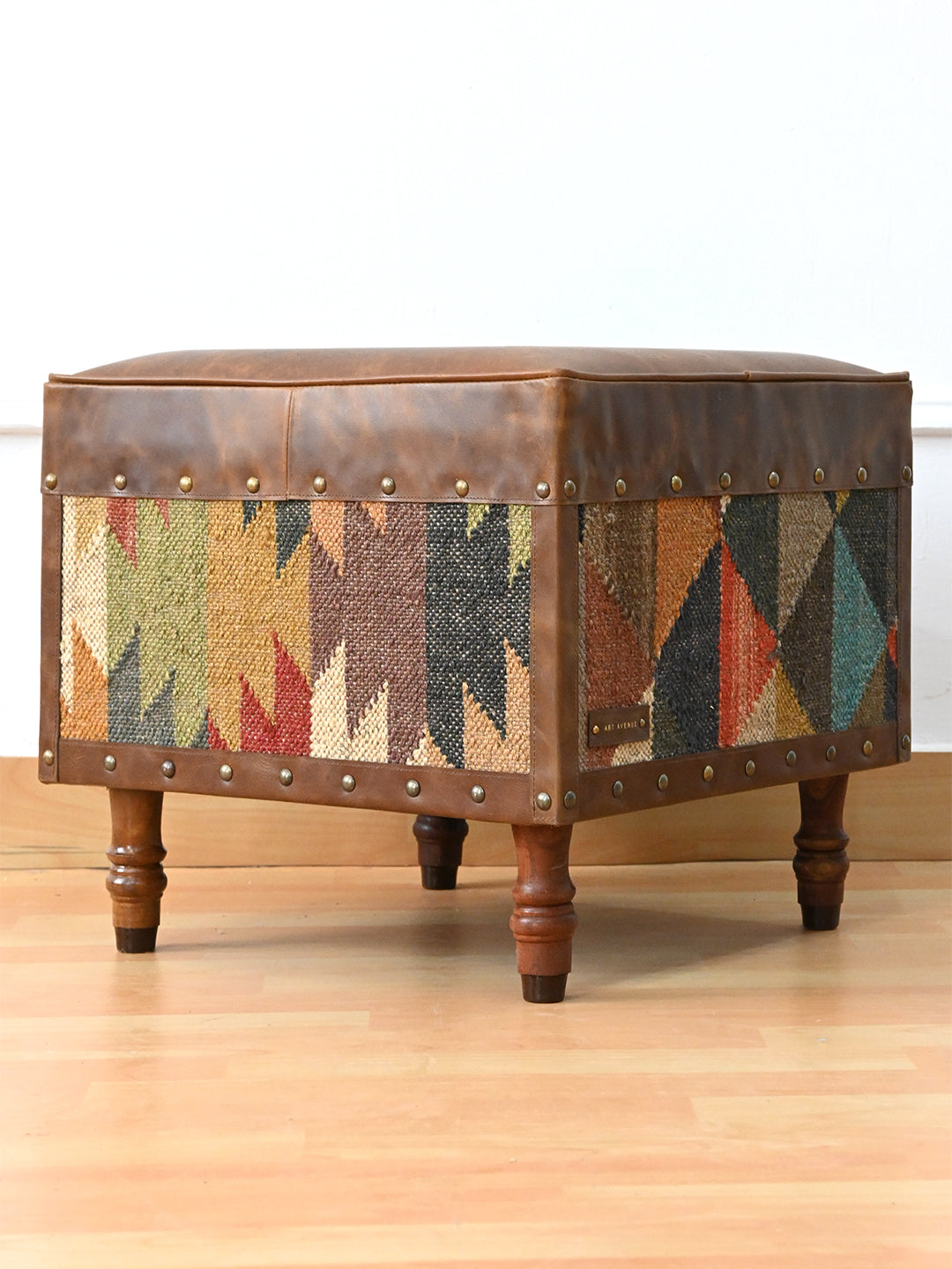Dundlod ottoman by Art Avenue in three-quarter view, stepped kilim motif on one side and triangle patchwork on the other