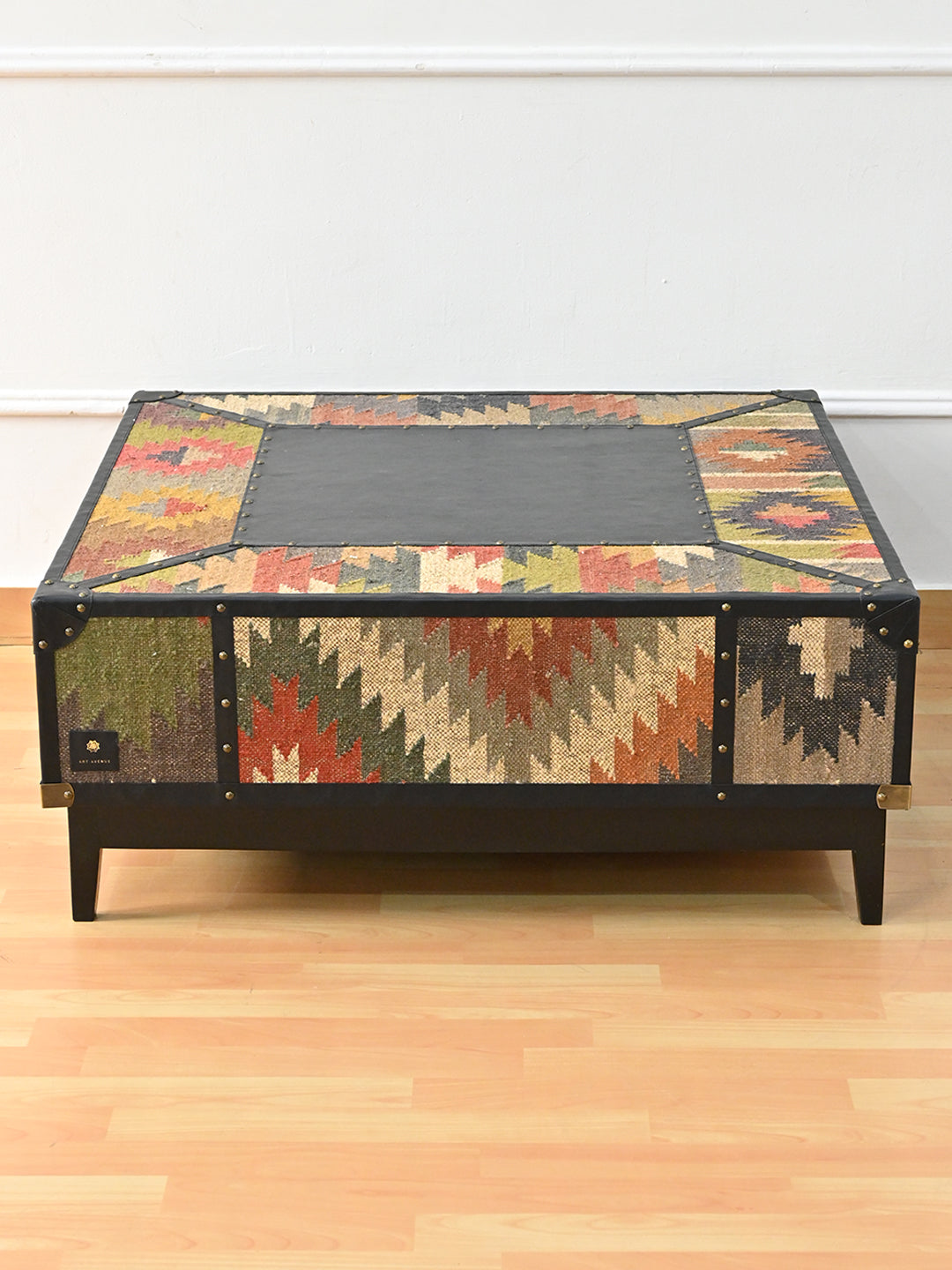 Mehrangarh coffee table from above and to the side, flat black leather top framed by mitred vintage kilim, Art Avenue