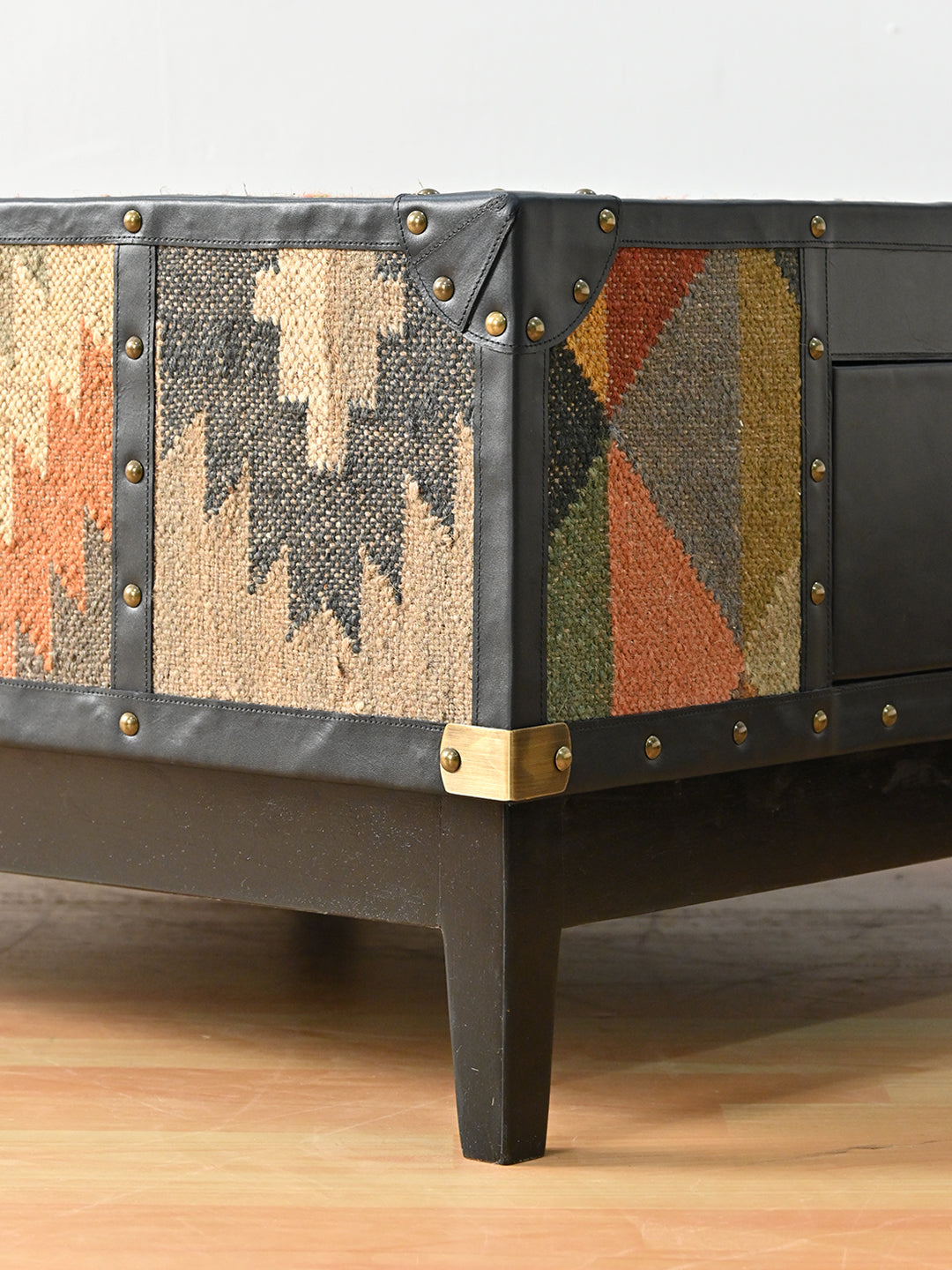 Base corner of the Mehrangarh coffee table, brass cap and tapered solid wood leg beneath studded leather binding, Art Avenue
