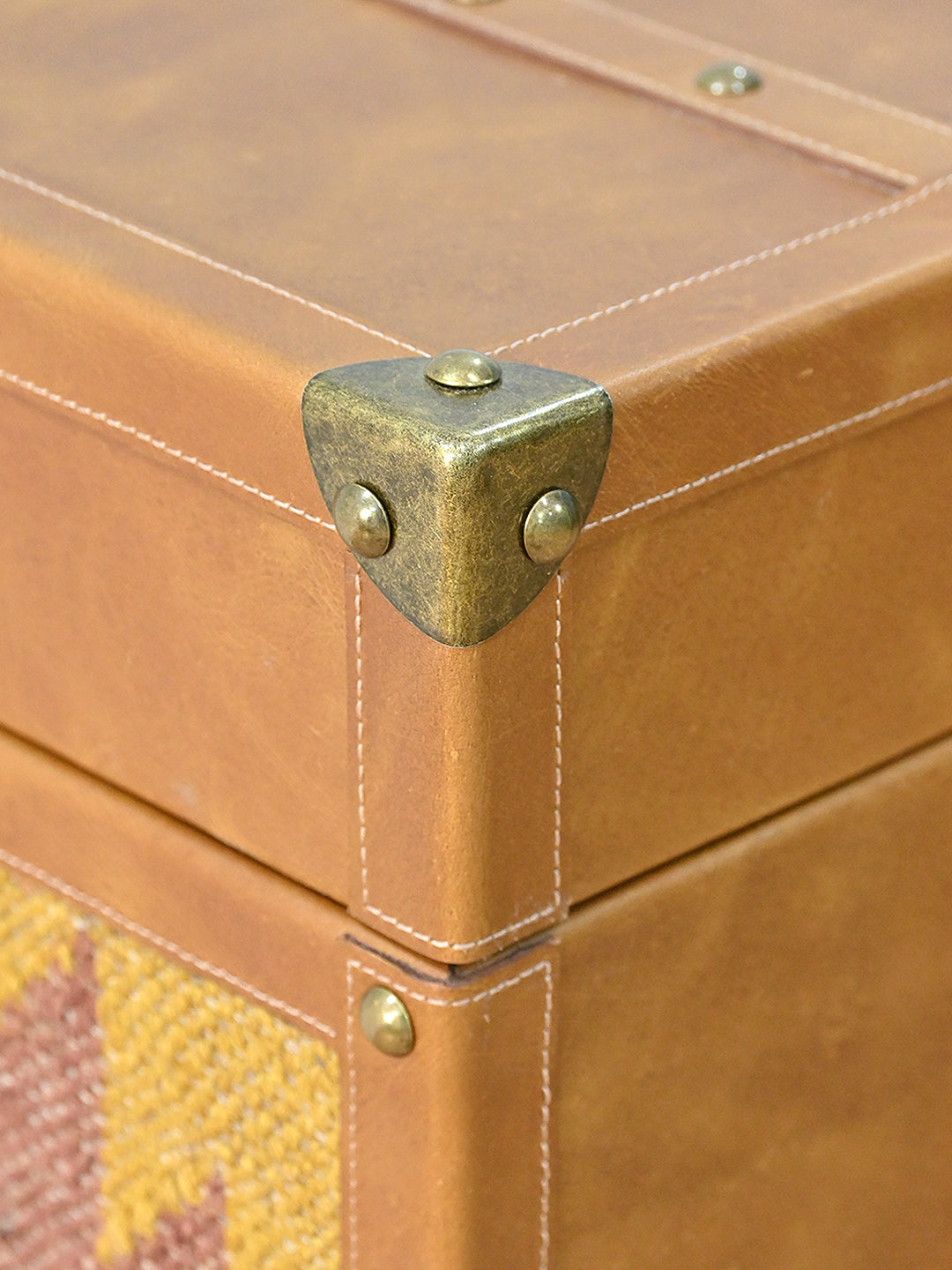 Riveted brass corner cap on the stitched leather edge of the Osian trunk. Art Avenue kilim and leather storage, made to order.