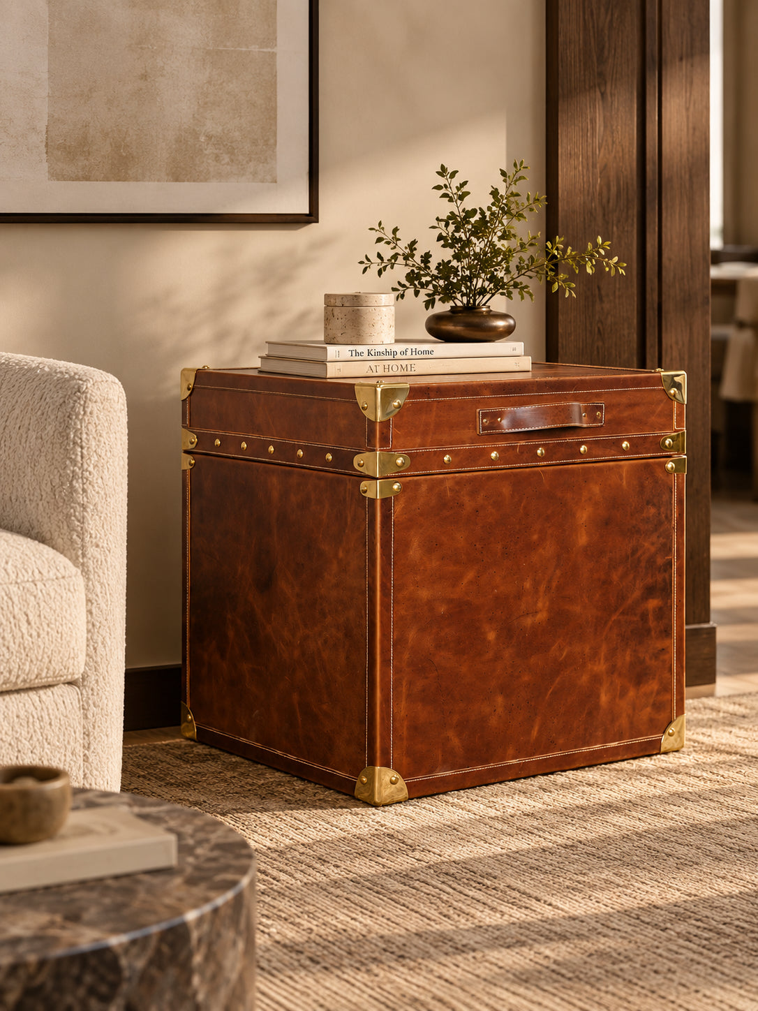 Cordoba Leather Cube Trunk styled as a side table beside a cream armchair in a living room