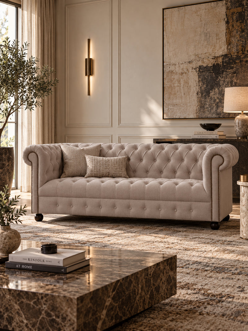 Hampstead fabric Chesterfield sofa in Pebble linen, angled three-quarter view showing the diamond-buttoned back, seat and skirt with brass-studded scroll arms — Art Avenue, made to order
