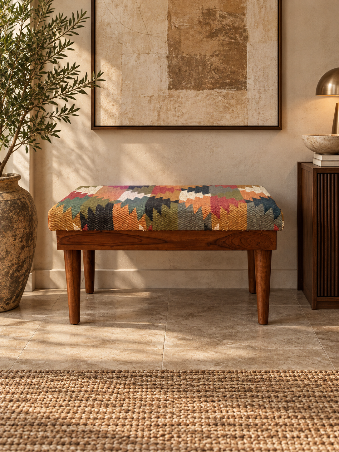 Front view of the Almora Kilim Bench against a plaster wall beneath framed artwork, kilim top and sides on a solid wood frame — Art Avenue