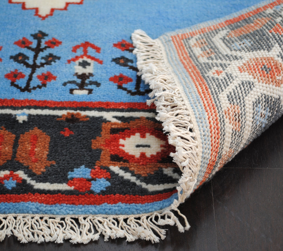 Corner of the Nilgiri hand-knotted rug turned over to show the knotted reverse, cotton fringe and charcoal rosette border, Art Avenue