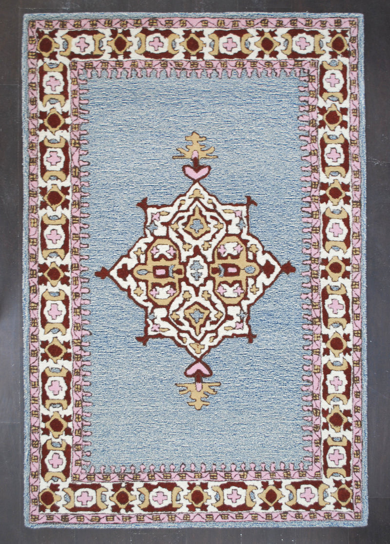 Lucknow hand-tufted rug in 100% New Zealand wool, full front view: star medallion in ivory, burgundy, sand-gold and rose pink on a heathered denim-blue field inside a wide ivory border, Art Avenue, 4×6 ft
