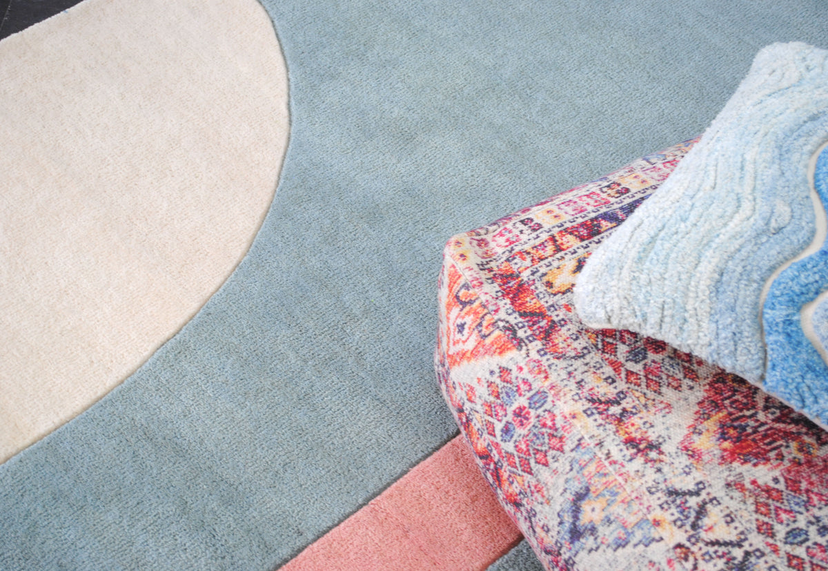 Pondicherry hand-tufted wool rug from above, the curve of the ivory arch and the end of the coral bar on the sea-glass blue field, Art Avenue