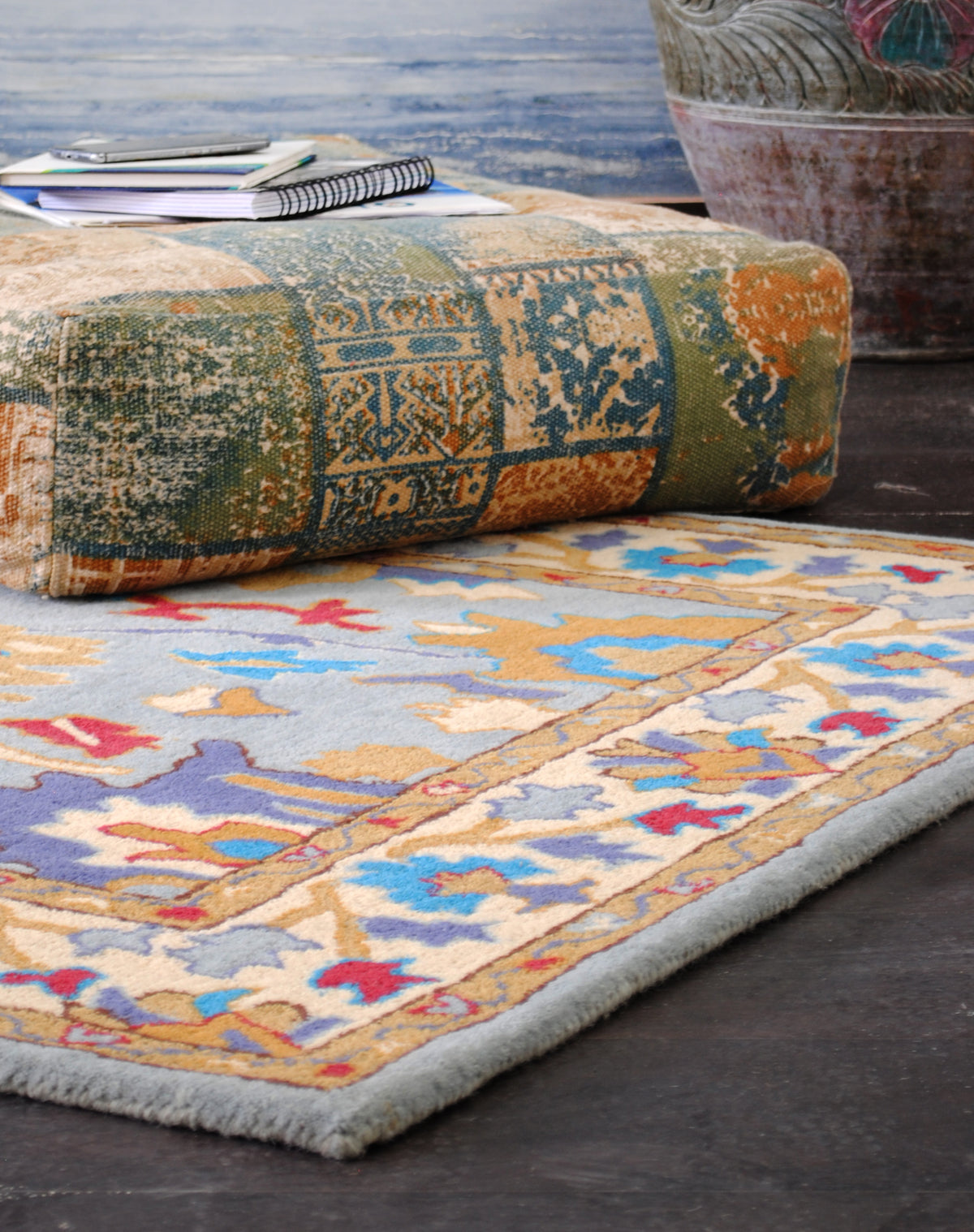 Close view of the Agra rug corner, showing the sky-blue field, ivory vine border and pale blue bound edge