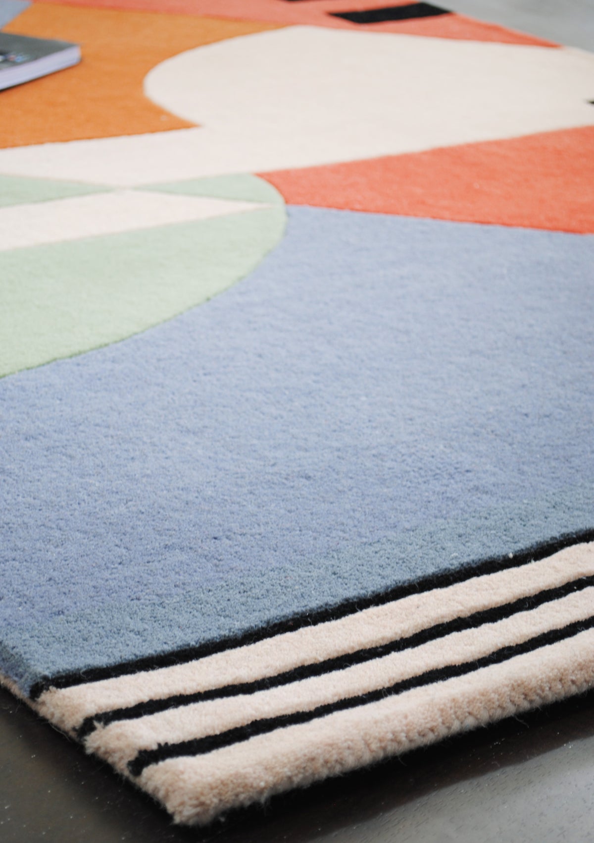 Goa rug corner, a sky-blue field meeting carved black-and-ivory stripes at the bound edge, Art Avenue