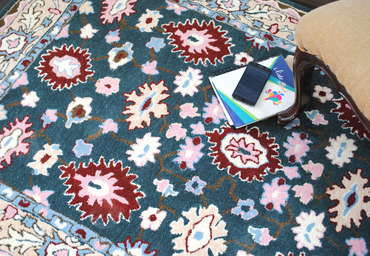 Srinagar wool rug field: crimson rosettes, ivory palmettes and rose, sky-blue and ivory blossoms on deep teal