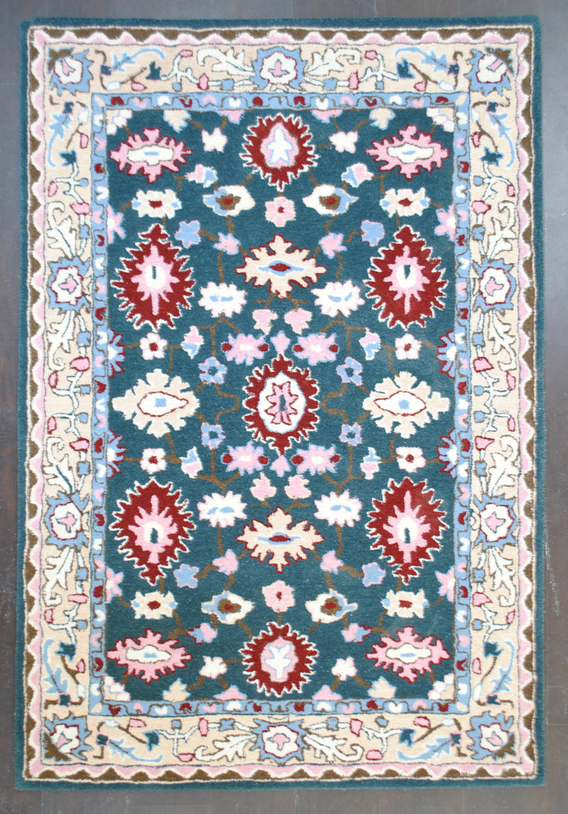 Srinagar hand-tufted rug in 100% New Zealand wool, full overhead view: crimson rosettes and ivory palmettes on a deep teal field with a cream vine border, Art Avenue, 4×6 ft