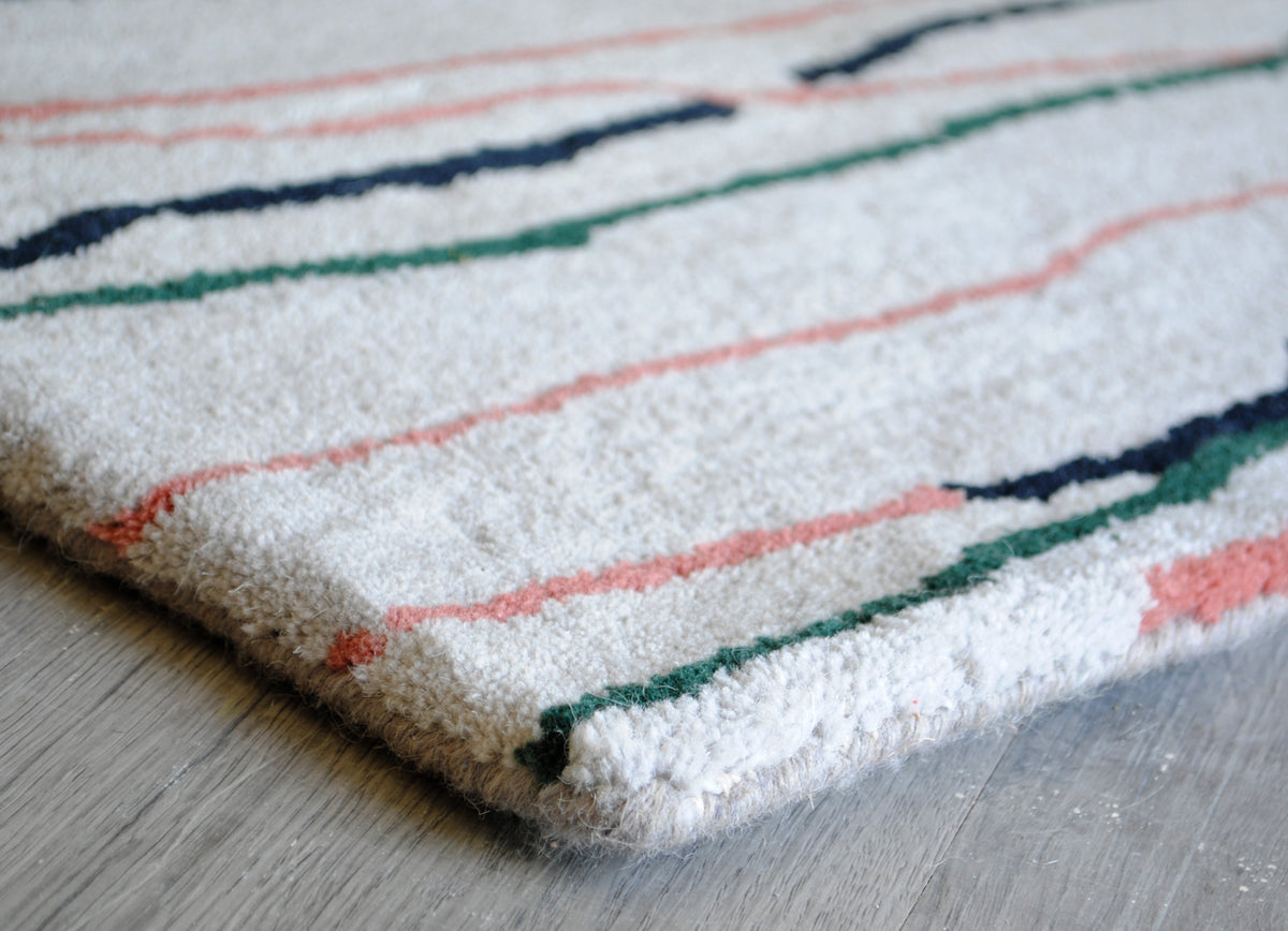 Corner of the Chilika rug folded back to show the cotton canvas backing and bound edge